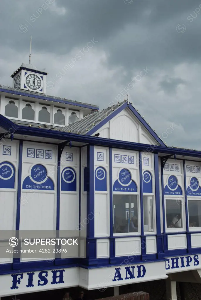 England, East Sussex, Eastbourne. A fish and chip shop on Eastbourne pier with threatening storm clouds above.