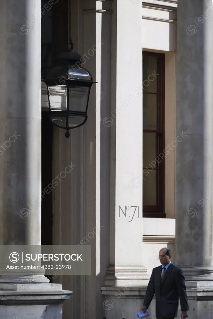 England, London, St James. A businessman passing the Oxford and Cambridge club at 71 Pall Mall.