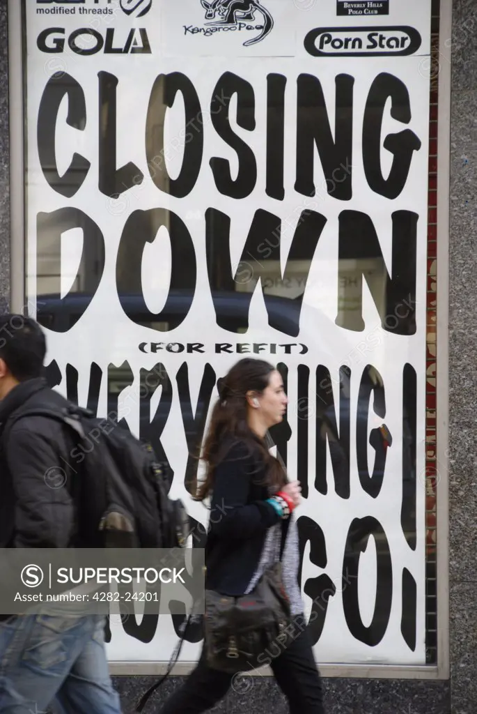 England, London, Oxford Circus. Shoppers passing a store advertising a closing down sale in Oxford Street.