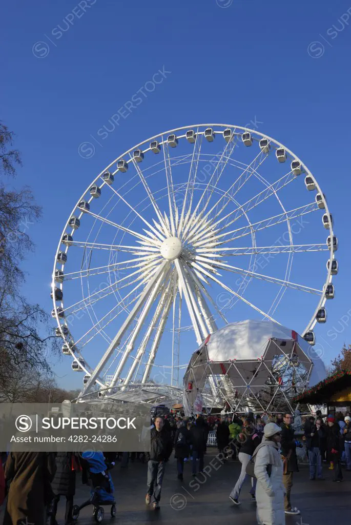 England, London, Hyde Park. Visitors at the Winter Wonderland funfair below The Wheel of Hyde Park.