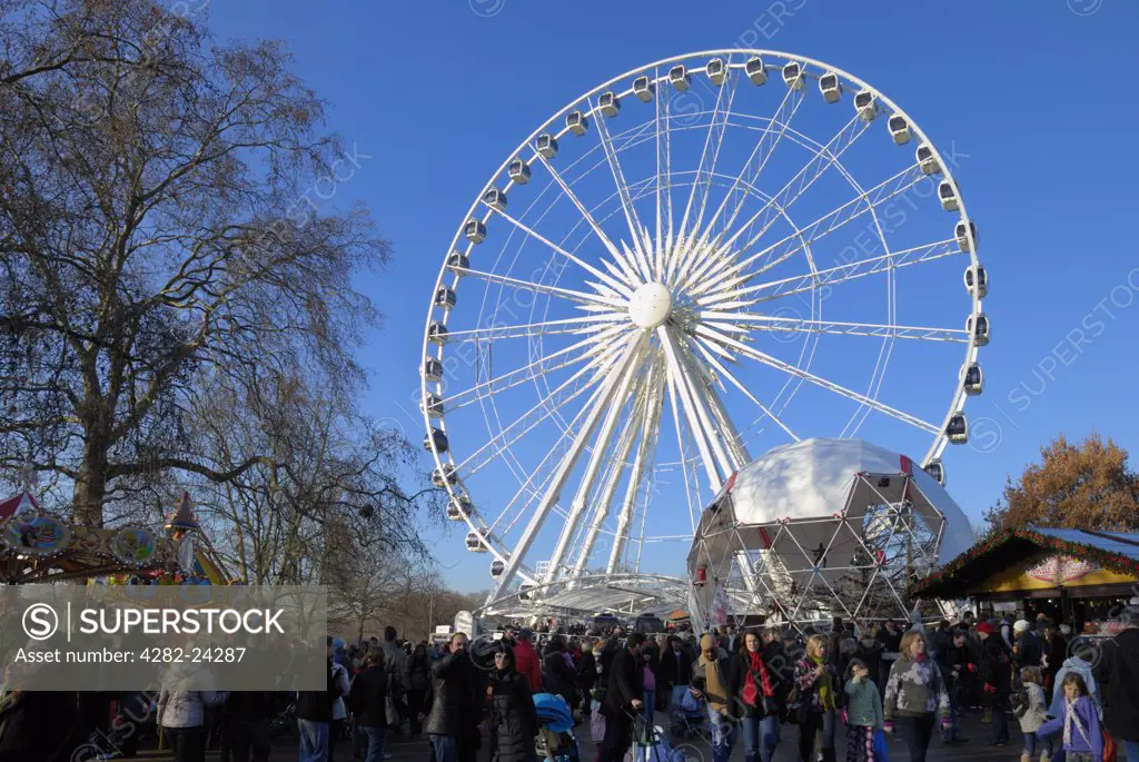 England, London, Hyde Park. Visitors at the Winter Wonderland funfair below The Wheel of Hyde Park.