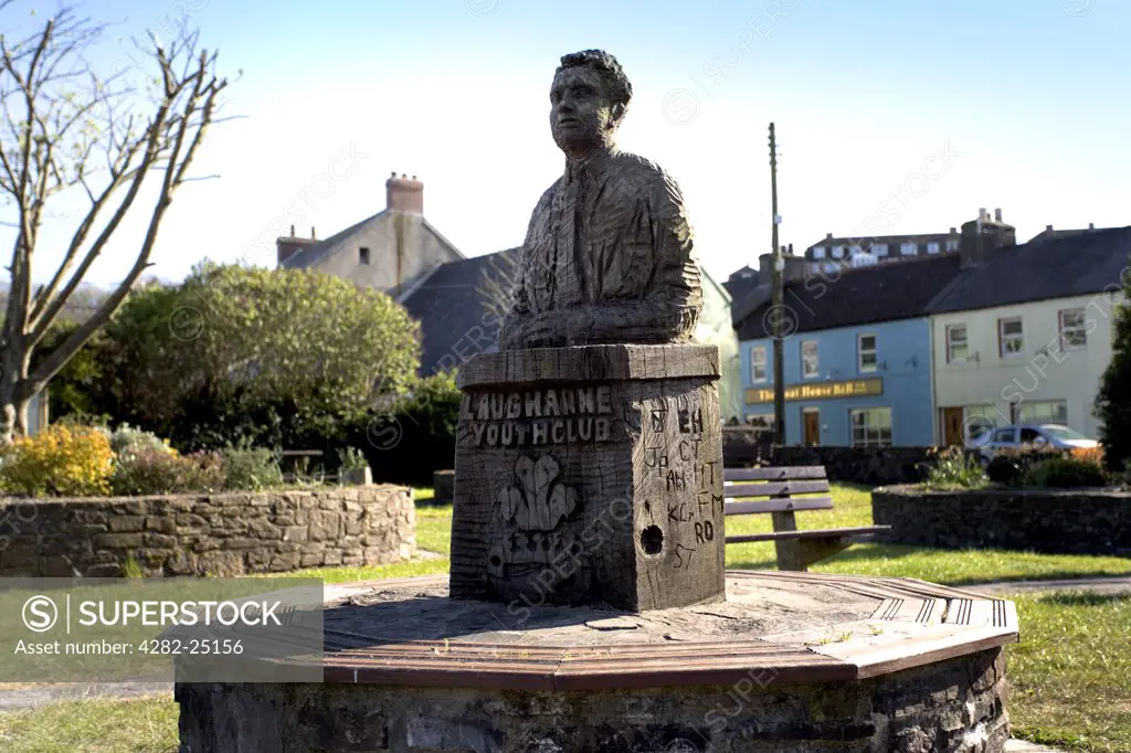 Wales, Carmarthenshire, Laugharne. A wooden bench and sculpture of Dylan Thomas. Laugharne was home to Wales' most famous poet and writer Dylan Thomas and both Thomas and his wife are burried in the local churchyard.