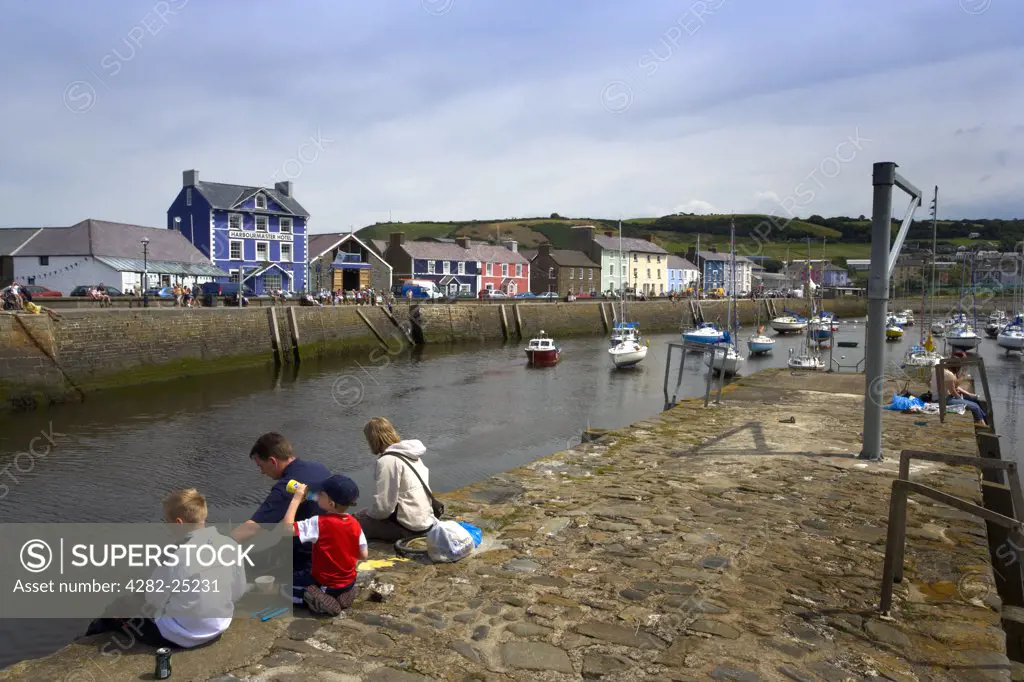 Wales, Ceredigion, Aberaeron. A family sitting on the quayside at Aberaeron.