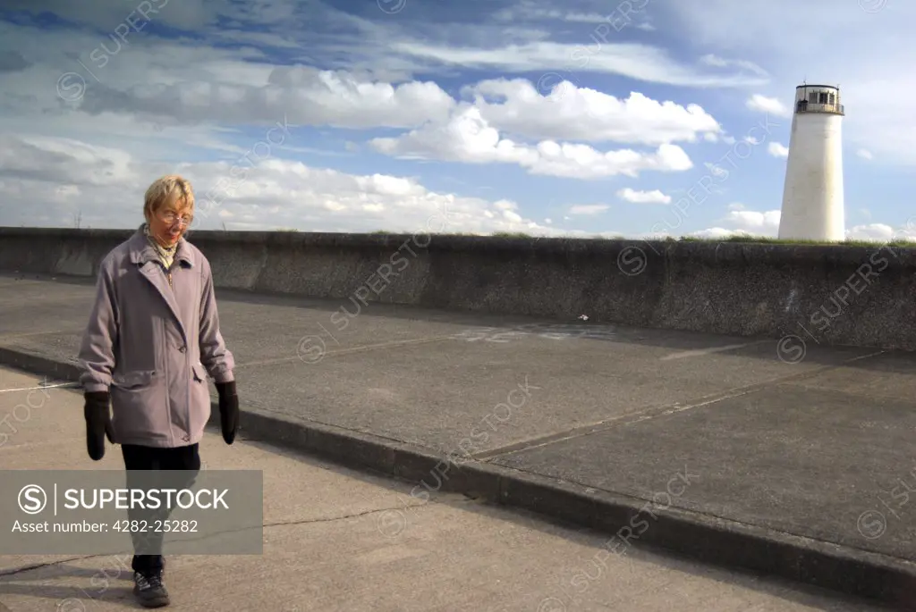 England, Merseyside, Wallassey. A woman walking by the sea.
