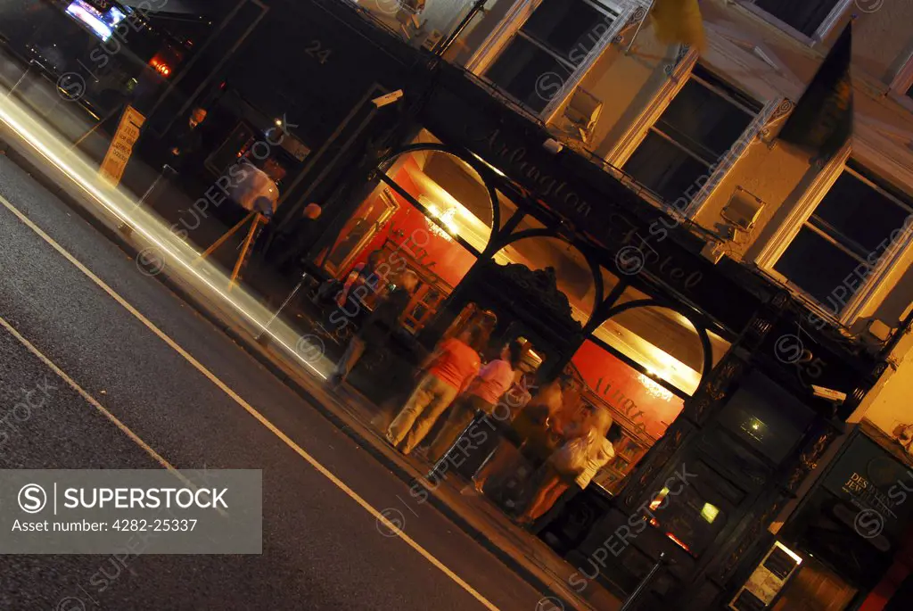 Republic of Ireland, Dublin, Central Dublin. A group of people outside the Arlington Hotel at night.