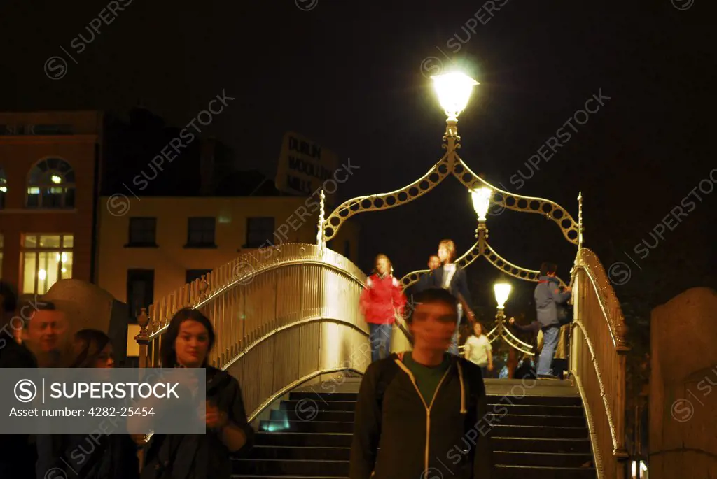 Republic of Ireland, Dublin, Ha'penny Bridge. People crossing Ha'penny bridge at night in Dublin.
