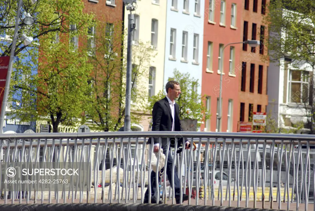 Republic of Ireland, County Cork, Central Cork. A man walking over a bridge on the River Lee in central Cork.
