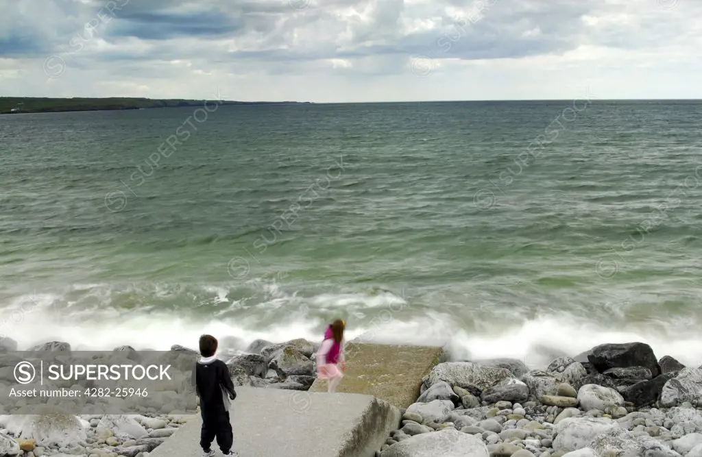 Republic of Ireland, County Clare, Lahinch. Children playing on the rocks at Lahinch in County Clare.