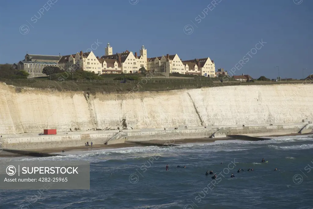 England, City of Brighton and Hove, Brighton. Surfers in the sea beneath white chalk cliffs near Brighton Marina.