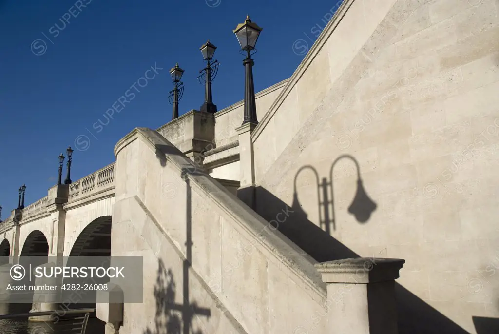 England, London, Kingston upon Thames. The shadow from an old street lamp on the stonework by steps leading up to Kingston Bridge.