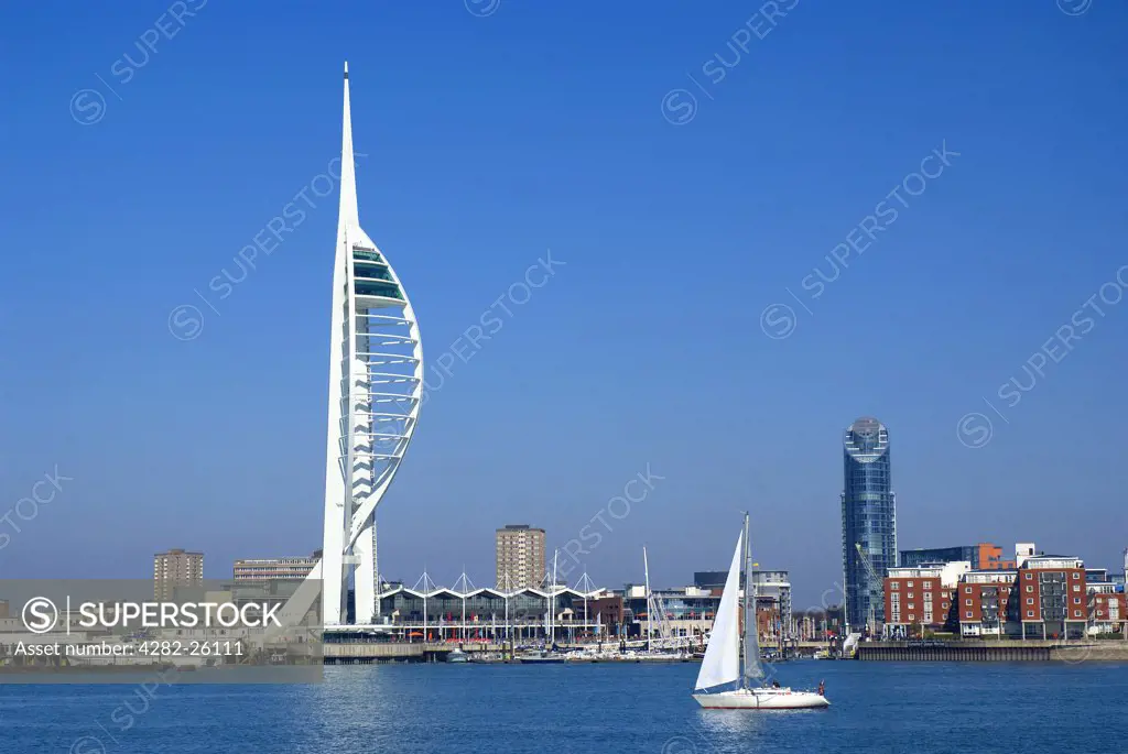 England, Hampshire, Portsmouth. A yacht sailing into Portsmouth Harbour past the 170m high Spinnaker Tower at Gunwharf Quays.