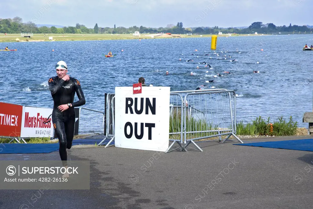 England, Berkshire, Windsor. A triathlete leaving the water and running towards the transition area at Eton Dorney, the venue for Rowing, Paralympic Rowing and Canoe Sprint events during the London 2012 Games.