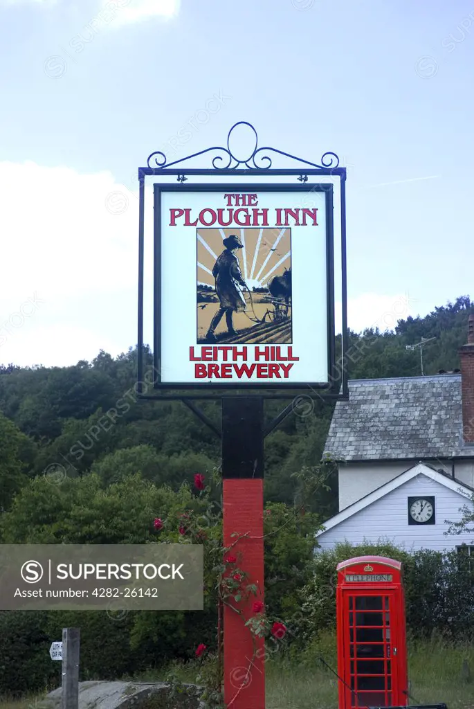 England, Surrey, Coldharbour. The Plough Inn pub sign and traditional red telephone box near Coldharbour.