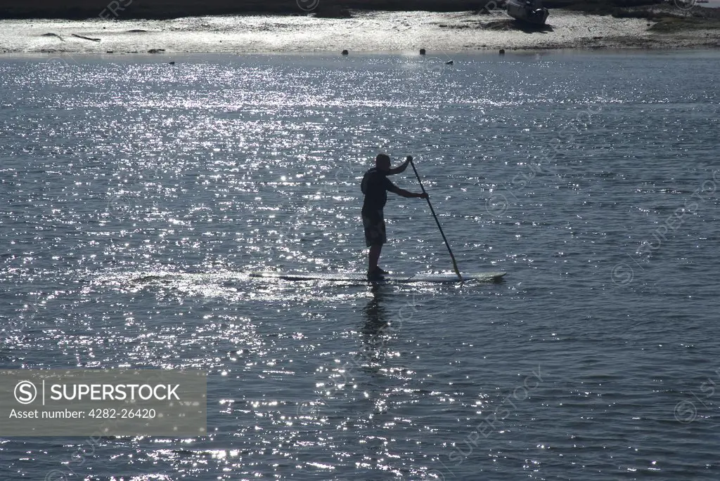 England, West Sussex, Shoreham-By-Sea. A lone paddle boarder making his way up the River Adur.