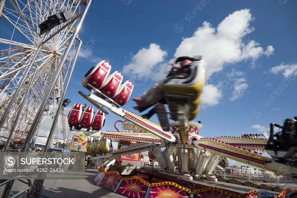 England, Lancashire, Blackpool. People enjoying a fairground at Blackpool. The town is believed to get its name from a drainage channel which ran over a peat bog making the water which ran into the sea black.