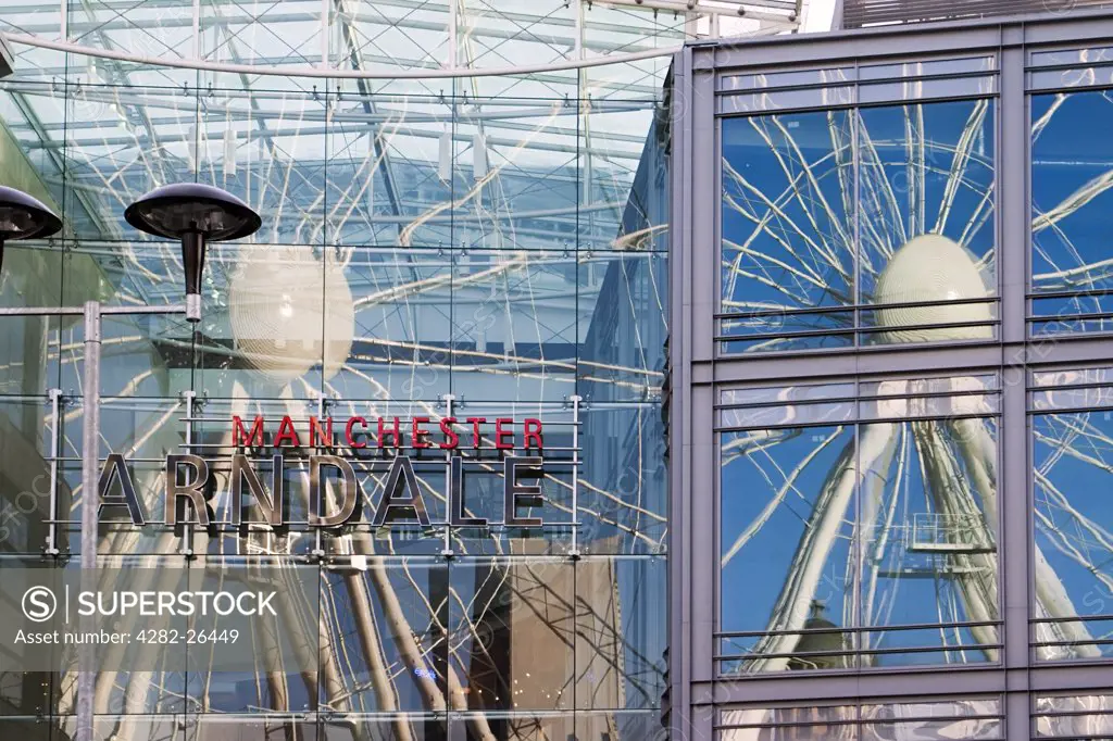 England, Greater Manchester, Manchester. The Manchester Wheel reflected in the glass windows of the nearby shops and Arndale centre. The wheel in Exchange Square is 60m high and weighs 365 tonnes.