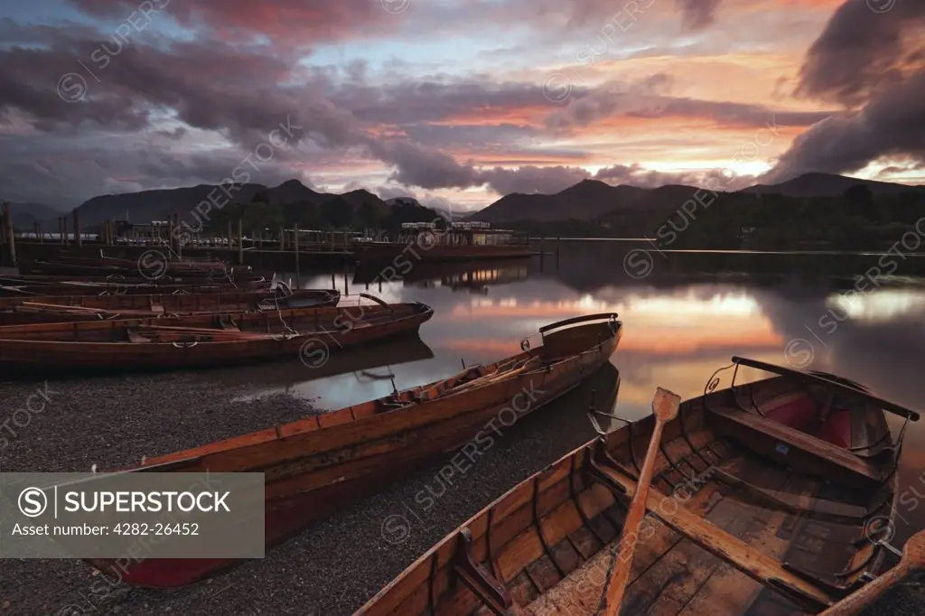 England, Cumbria, Derwent Water. Boats moored on the banks of Derwent Water at sunset. Watched over by the fells of Derwent, and Castlerigg, the lake was described by John Keats as being shut in with rich-toned mountains.