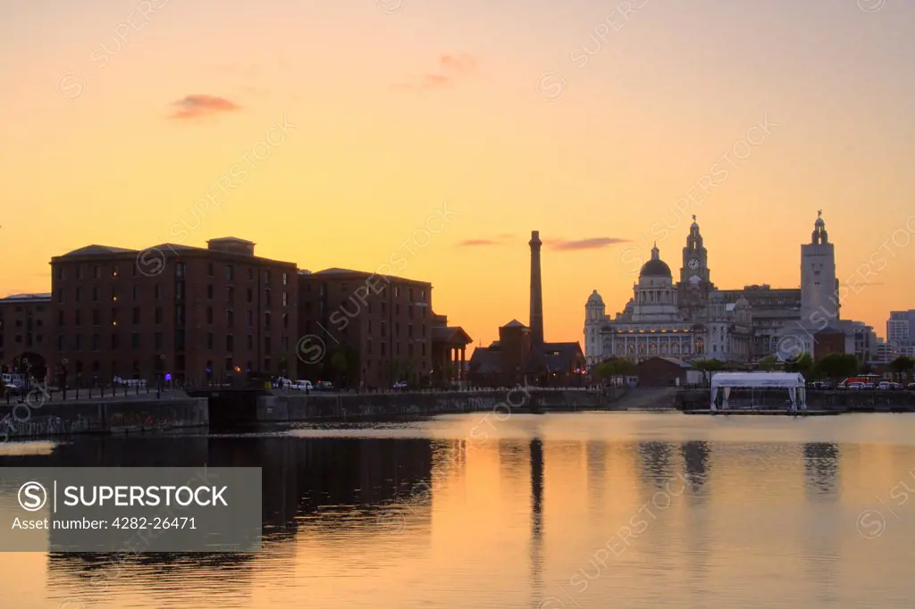 England, Merseyside, Liverpool. View at sunset across the Albert Dock to the Liver Building and the Three Graces.