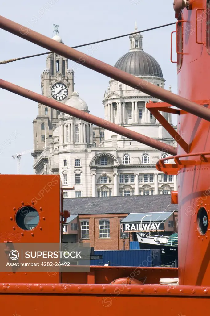 England, Merseyside, Liverpool. Bright orange boat moored in Liverpool docks with the Liver Building in the distance.
