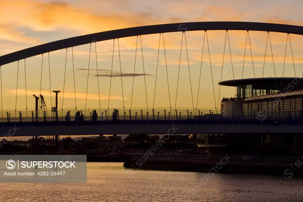 England, Greater Manchester, Salford Quays. Outline of Salford Quays Millennium Bridge at sunset.