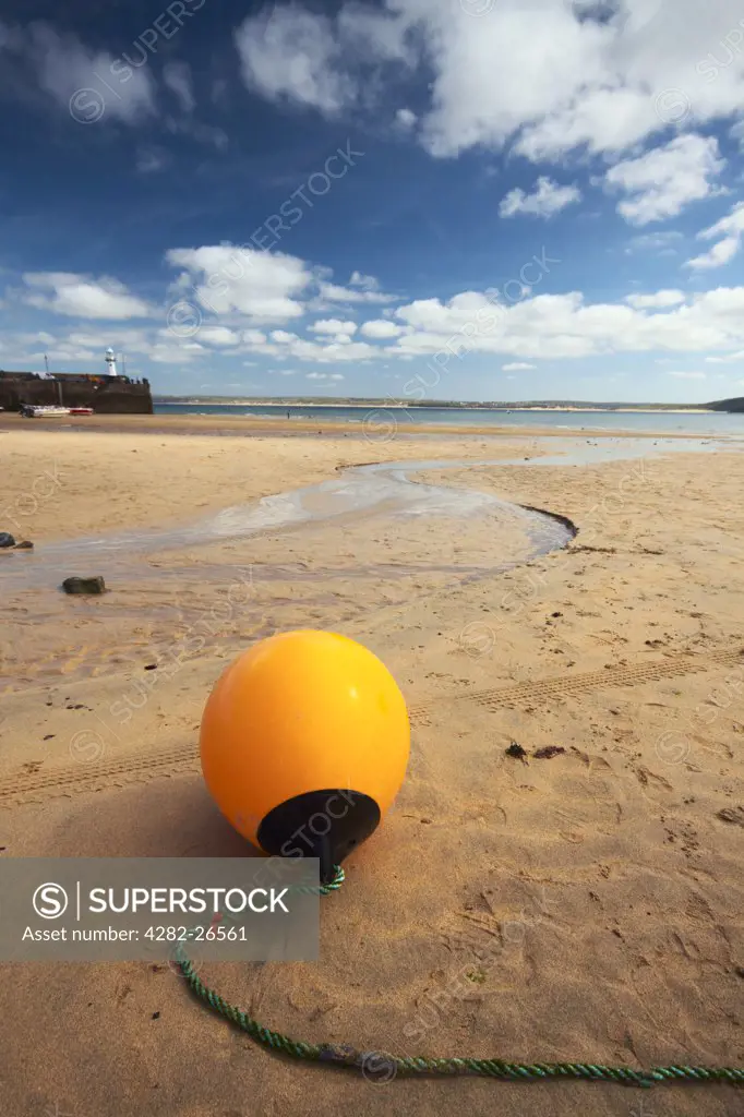 England, Cornwall, St Ives. A yellow marker buoy lying on the sandy beach at St Ives.