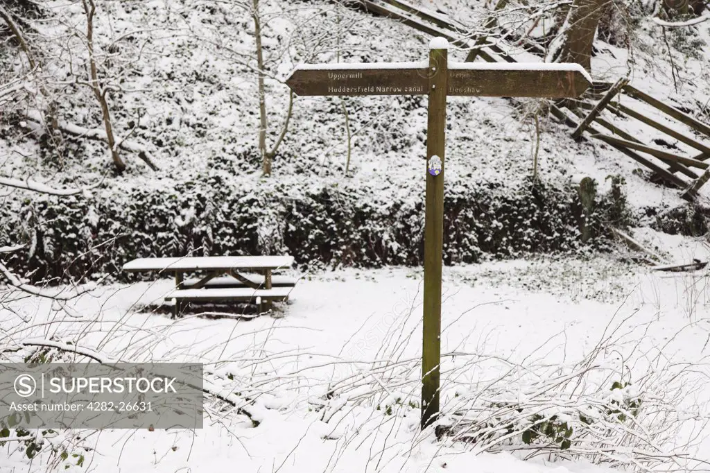 England, Lancashire, Saddleworth. Signpost and picnic bench covered in snow.