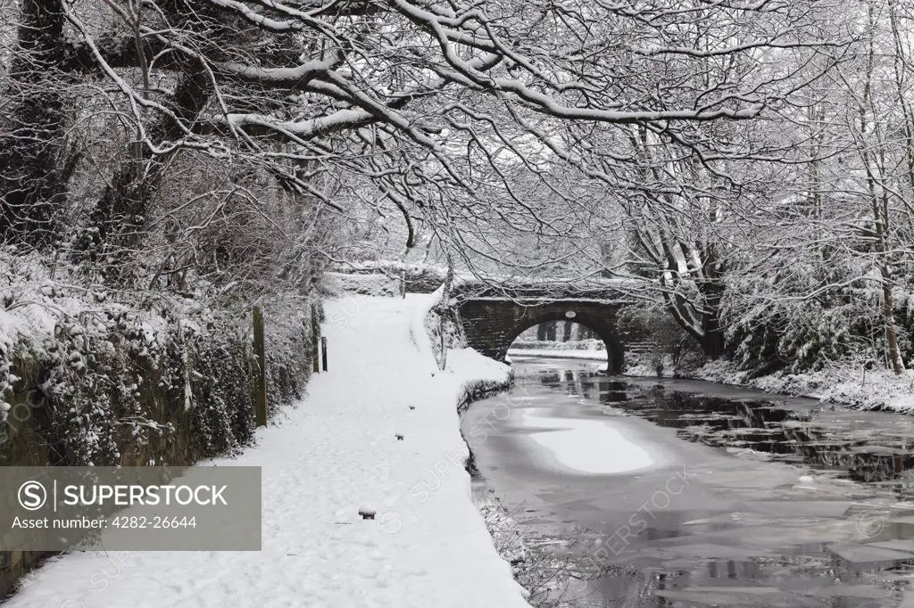 England, Lancashire, Saddleworth. A snow covered towpath and sheets of ice on the surface of the Huddersfield Narrow Canal.