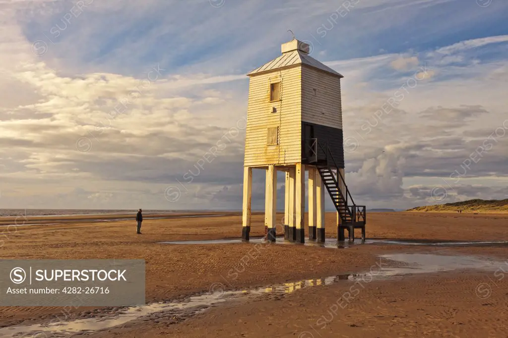 England, Somerset, Burnham-On-Sea. A man standing on the beach looking at Burnham-on-Sea Low Lighthouse, built by Joseph Nelson in 1832.