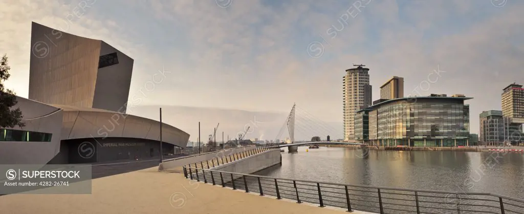 England, Greater Manchester, Manchester. Panoramic waterside view across Salford Quays featuring the Imperial War Museum North (IWM North), The Lowry Bridge and MediaCityUK development.