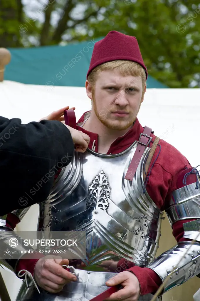 England, Essex, Castle Hedingham. A young soldier being prepared for battle in a medieval re-enactment at Hedingham castle.