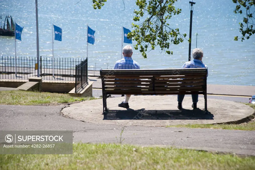 England, Essex, Southend-on-Sea. An elderly couple sitting on a bench looking out to sea at Southend-on-Sea.