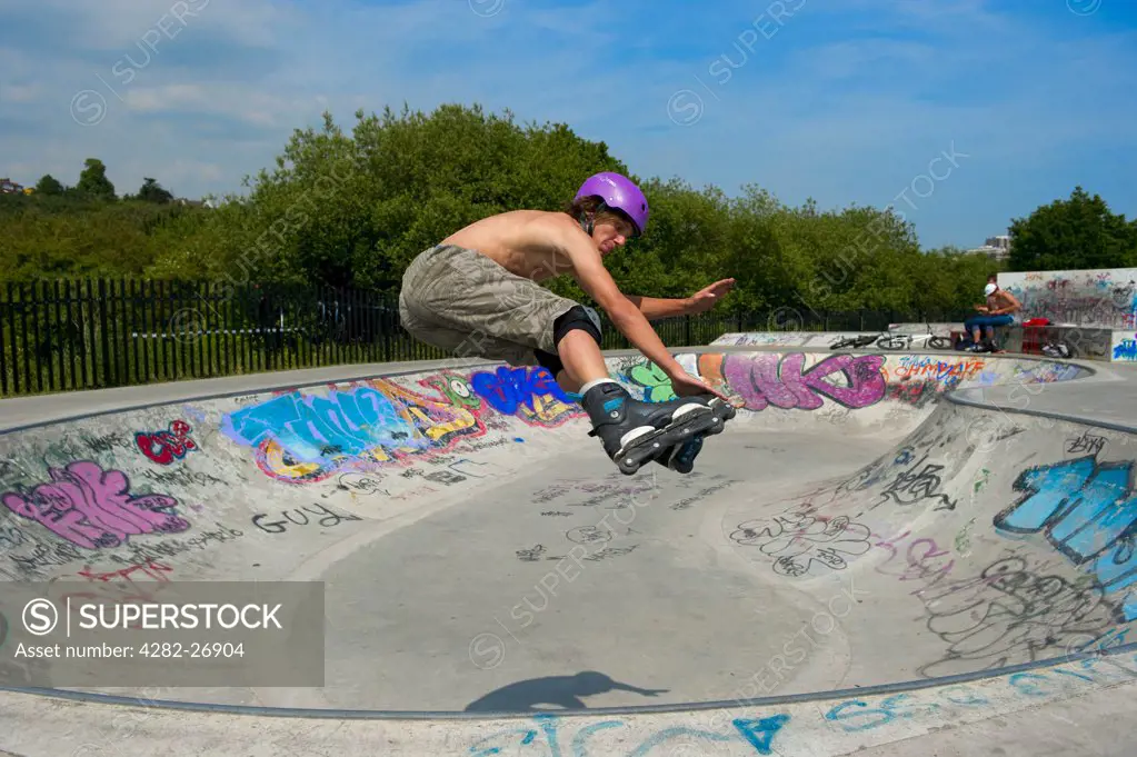 England, Essex, Leigh-on-Sea. Teenage rollerblader (in-line skater) performing stunts at a purpose built skatepark.