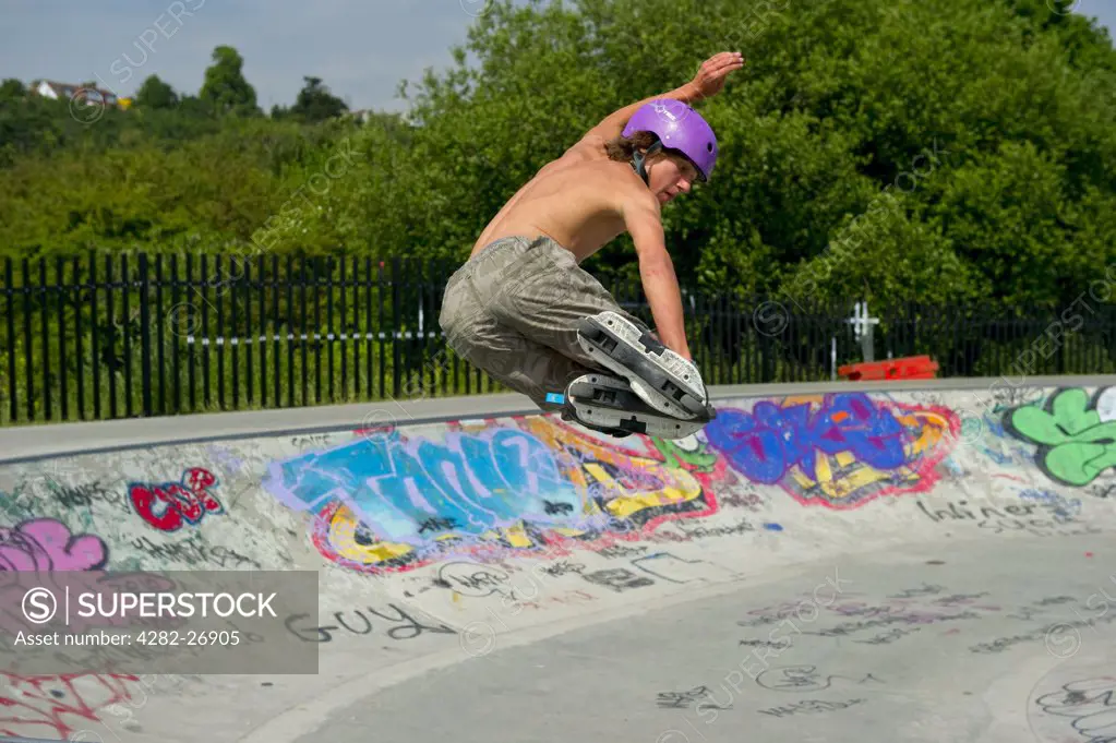 England, Essex, Leigh-on-Sea. Teenage rollerblader (in-line skater) performing stunts at a purpose built skatepark.