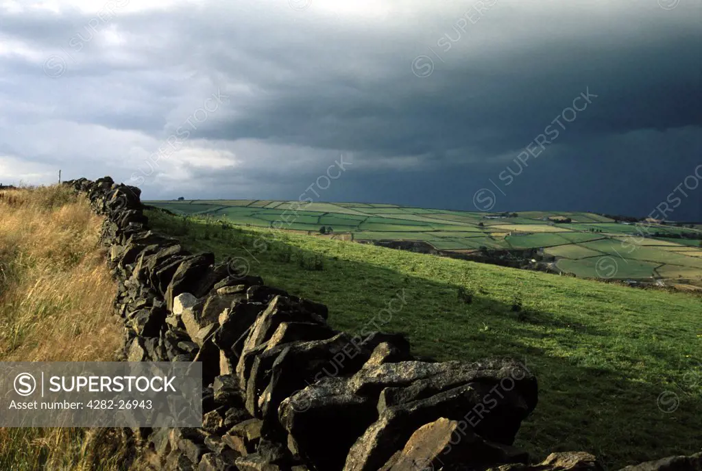 England, West Yorkshire, Holmfirth. Pennine fields viewed over a dry stone wall. One of the earliest recorded dry stone walls was discovered in 2000BC.