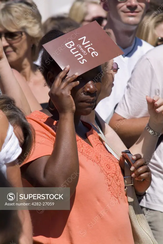 England, East Sussex, Brighton. A woman shields her eyes from the sun whilst watching the Brighton Gay Pride parade.