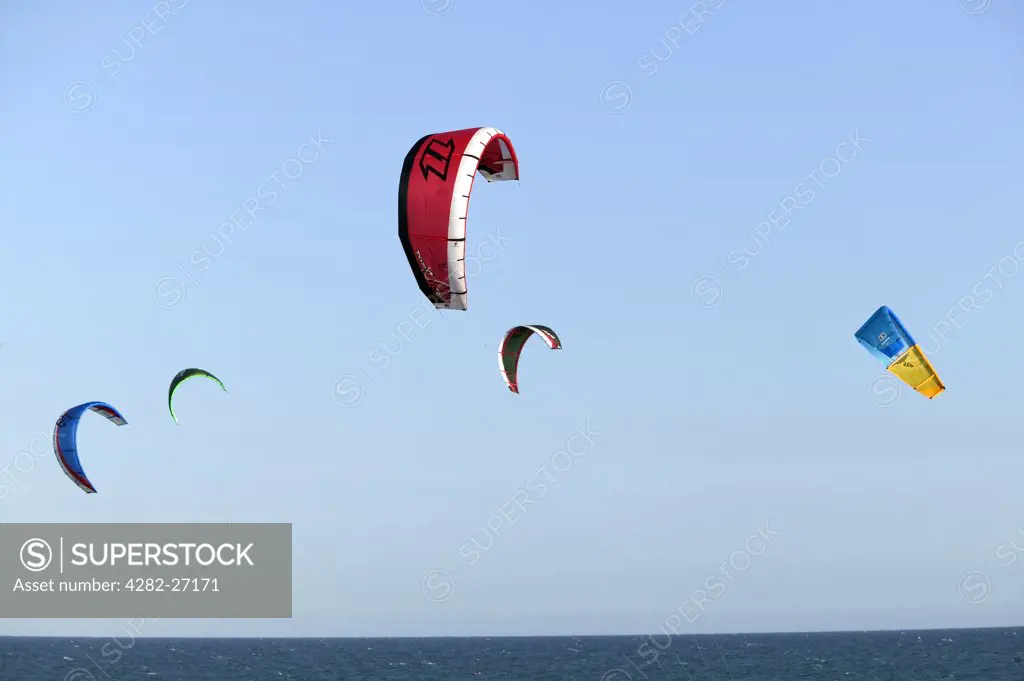 England, East Sussex, Brighton. Kite surfing off Brighton Beach. The sport involves using a power kite to pull the rider through the water on a small surfboard.