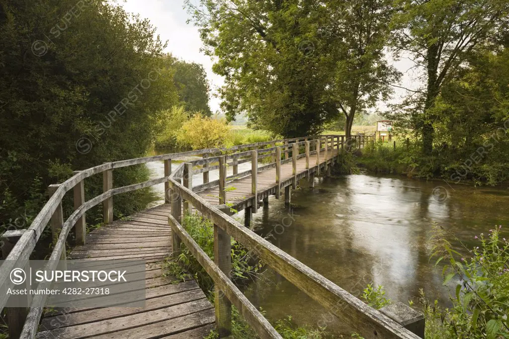 England, Hampshire, Chilbolton. A wooden footbridge over the River Test leading to Chilbolton Cow Common.