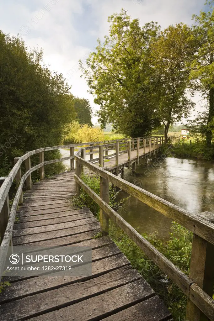 England, Hampshire, Chilbolton. A wooden footbridge over the River Test leading to Chilbolton Cow Common.