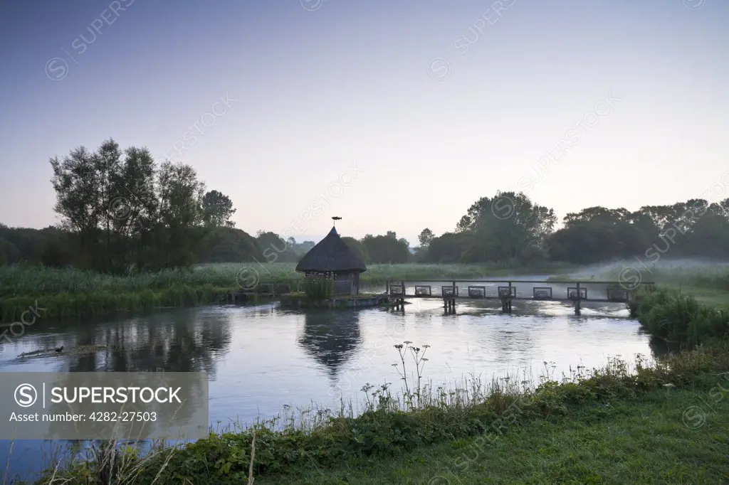 England, Hampshire, Longstock. Thatched fishing hut and Eel traps on the River Test at Longstock.