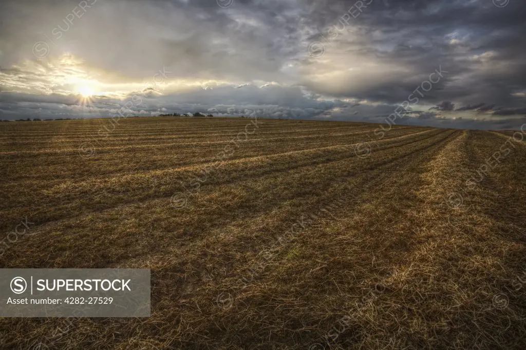 England, Nottinghamshire, Nottingham. Sunset in a stormy sky over a recently ploughed field.