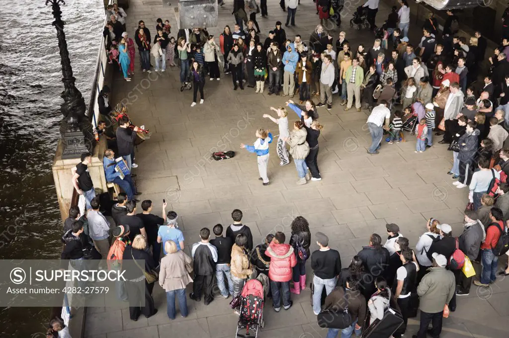 England, London, South Bank. A group of girls dancing to music played by street performers on the South Bank.