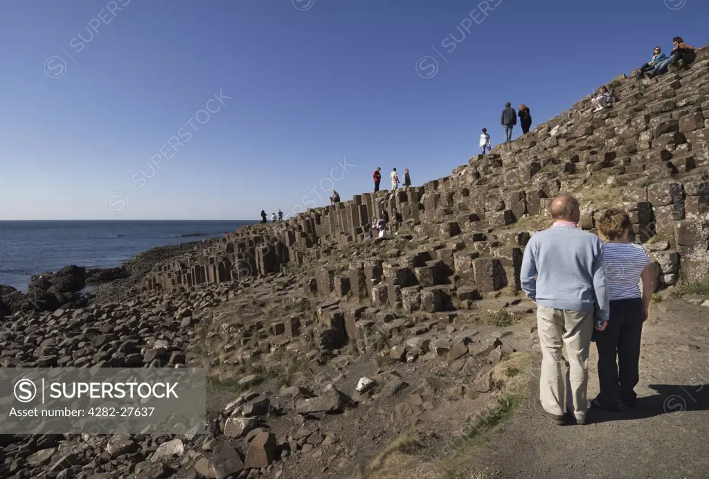 Northern Ireland, County Antrim, Giants Causeway. Tourists enjoying the wonder of the Giants Causeway, formed from 40,000 interlocking basalt columns. The Giants Causeway is a World Heritage Site and National Nature Reserve.