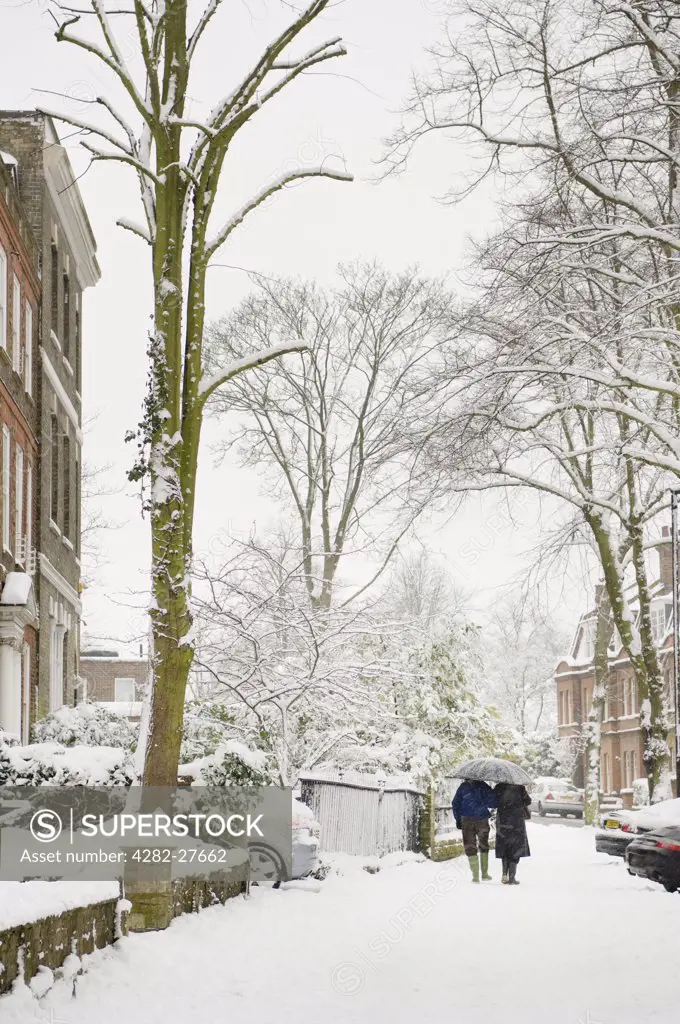 England, London, Camden. A couple walking along snow covered streets in Camden.