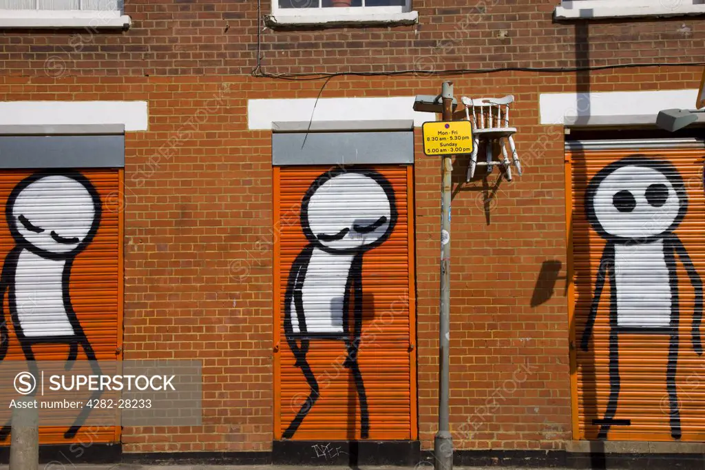 England, London, Brick Lane. Graffiti of people characters on shuttered doors in Brick Lane.