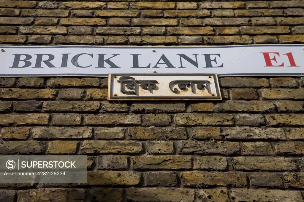 England, London, Brick Lane. Looking up to the Brick Lane street sign on a brick wall in East London.