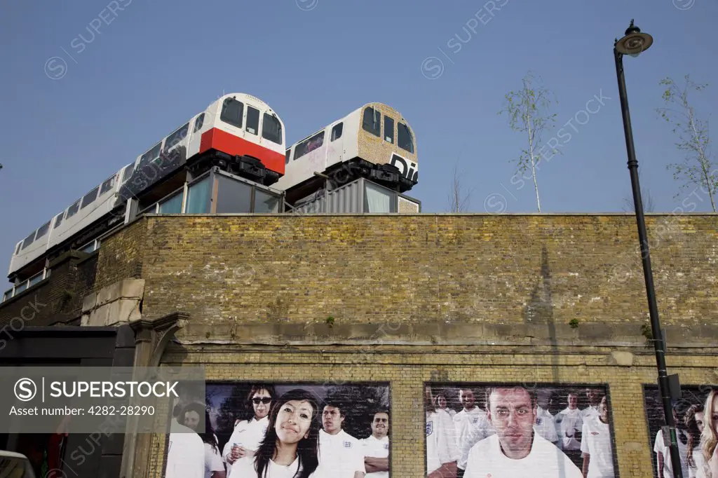 England, London, Shoreditch. Looking up to two tube carriages being used as offices on the top of a building in East London.