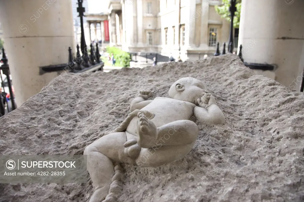 England, London, Trafalgar Square. A sculpture of a new born baby in a block of concrete outside St Martin in the Fields near Trafalgar Square.