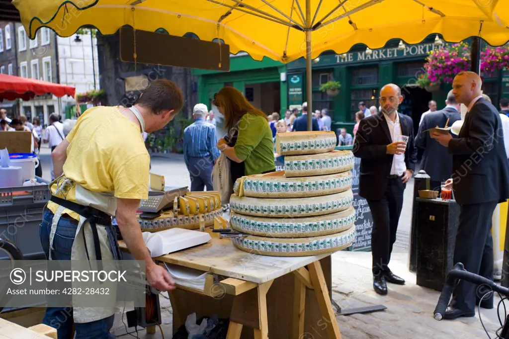 England, London, Borough. A market trader selling Cheese from the round in Borough Market.