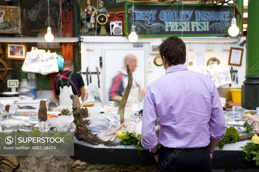 England, London, Borough. A customer at a fresh fish stall in Borough Market.