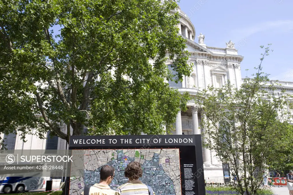 England, London, City of London. Tourists examining a street map outside St Paul's Cathedral.